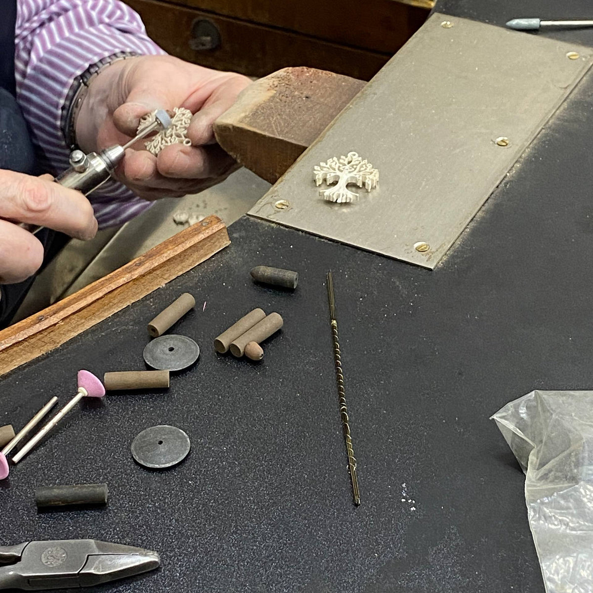 Person working with jewelry tools and materials on a workbench