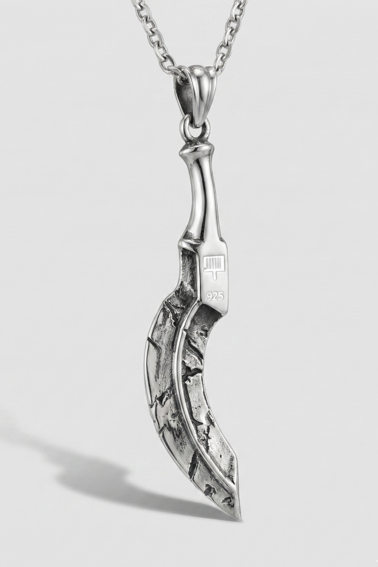 Silver pendant on a chain against a light gray background