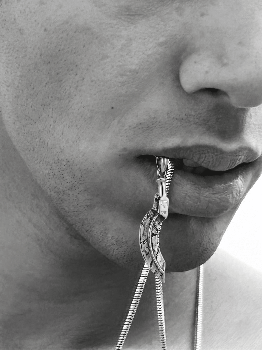 Close-up of a person wearing a silver chain necklace with an intricate design.